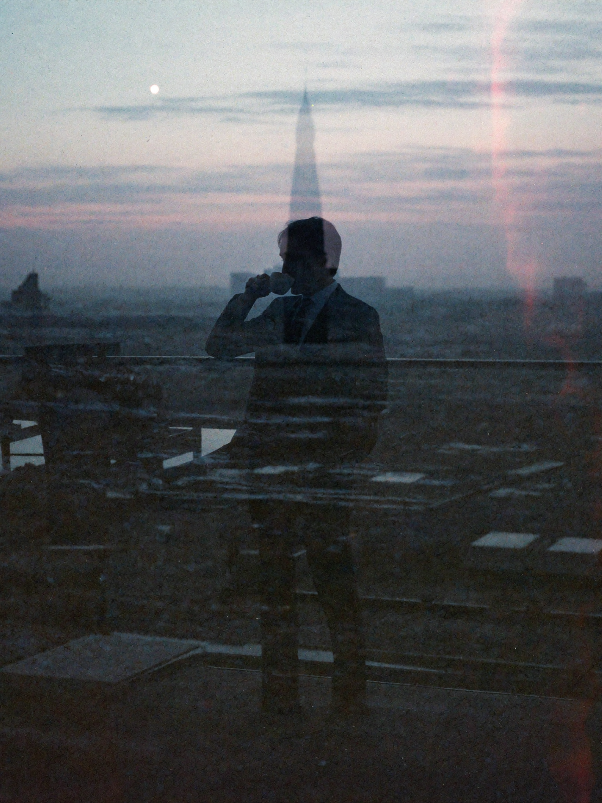 Rooftop, coffee in hand, city reflected